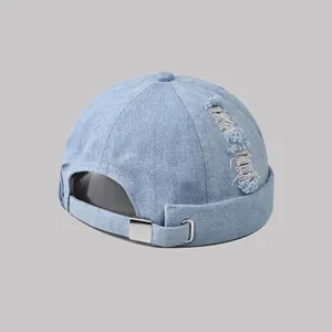 Dettaglio del berretto docker in denim lavato azzurro con fori vintage e fibbia metallica
