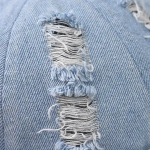 Dettaglio macro della trama usurata e dei bordi sfrangiati sul cappello in denim azzurro
