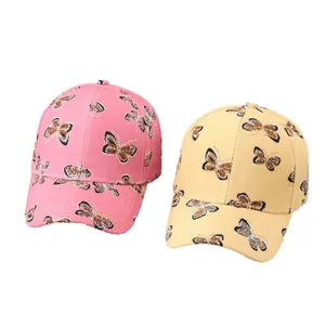 Pink and yellow baseball caps with butterfly and leopard patterns on a white background