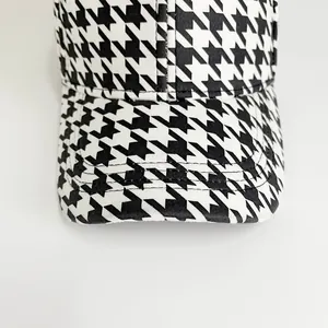 Detailed view of black and white houndstooth pattern fabric on a stylish baseball cap