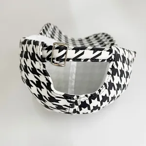 Detail view of houndstooth baseball cap featuring a silver metal adjustable buckle strap