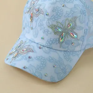 Detail view of light blue lace baseball cap with sparkling rhinestone butterflies