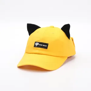 Dettaglio cappello baseball giallo in cotone con orecchie di gatto nere e toppa
