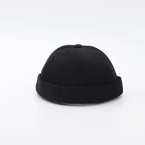 Detalle de gorro docker negro de seis paneles con borde enrollado y botón decorativo