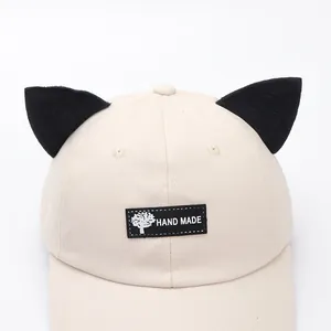 Dettaglio del cappello in cotone fatto a mano con orecchie di gatto nere e toppa ricamata