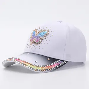 Close-up of rhinestone butterfly on white baseball cap with vibrant gradient crystal detail