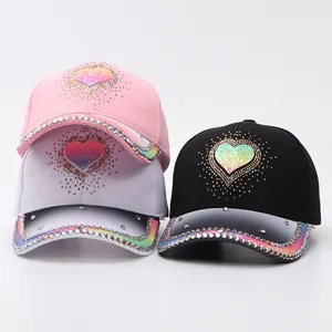 Detail of rhinestone baseball caps featuring gradient heart patterns in pink white and black