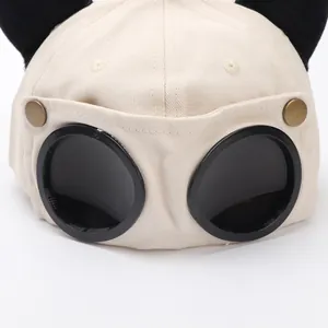 Dettaglio del cappellino da baseball beige con orecchie di gatto e occhiali da aviatore