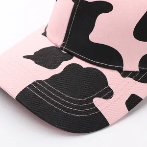 Primer plano de gorra rosa con estampado de vaca y detalles de costuras blancas en la visera