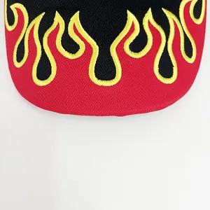 Close-up of detailed black and yellow flame embroidery on a red cotton baseball cap brim