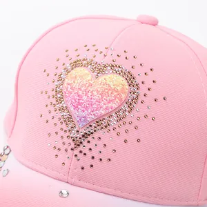 Detail of pink baseball cap featuring rhinestone heart and gradient glitter design