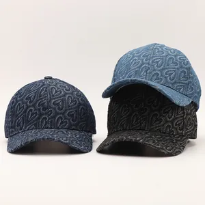 Detailansicht von Denim-Baseballcaps mit strukturierten Herzmustern in verschiedenen Waschungen