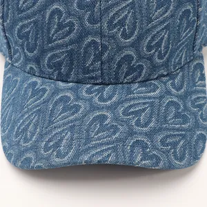 Detailaufnahme der blauen Denim-Baseballkappe mit weißem Herzmuster und feinen Nähten