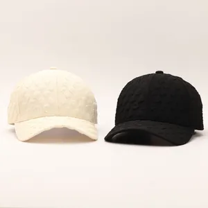 Detailed view of seersucker baseball caps with 3D heart embossed texture in beige and black