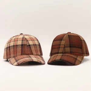 Detail of wool houndstooth baseball caps in beige and dark brown plaid textures