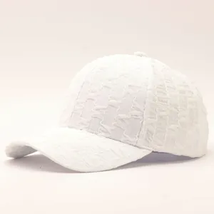 Detail shot of white seersucker baseball cap showing textured bubble fabric and curved brim