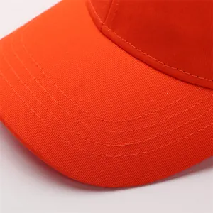 Détail d'une casquette orange montrant le sergé de coton et les coutures de la visière