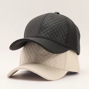 Detail of stacked quilted PU leather baseball caps in black and cream with diamond patterns