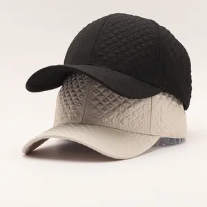 Close-up of geometric diamond-embossed texture on black and beige baseball caps