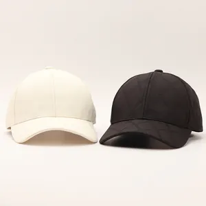 Detail of plaid quilted baseball caps in beige and black colors with textured diamond pattern