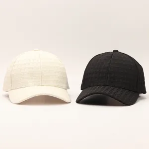 Detailed view of textured plaid baseball caps in beige and black with embossed grid pattern