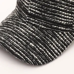 Close-up detail of black and white tweed fabric and stitching on a baseball cap