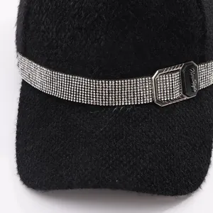 Detail of mink fur baseball cap featuring rhinestone band and engraved metal buckle