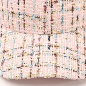 Macro shot of pink and blue tweed baseball cap featuring metallic gold yarn textures