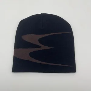 Close-up of black knitted beanie featuring brown abstract wavy patterns and soft textures