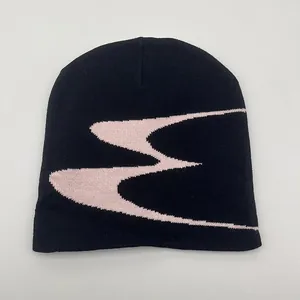 Close-up of black knitted beanie featuring pink geometric jacquard pattern details