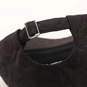 Macro detail of black baseball cap with floral embossing and silver metal adjustment buckle