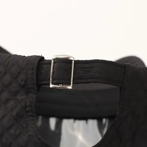 Close-up of black plaid baseball cap featuring a silver metal buckle and quilted texture