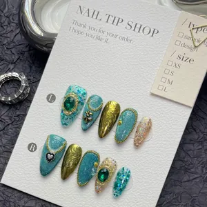 Exotic cat-eye press-on nails set with emerald rhinestones and gold relief details