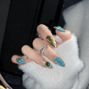 Handmade emerald and gold press-on nails with luxury rhinestones and cat-eye finish