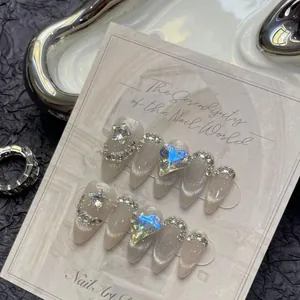 Detail of almond cat-eye press-on nails with 3D star and heart rhinestone embellishments