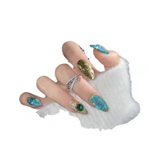 Exotic cat eye press-on nails in blue and gold with emerald gems and glitter detail