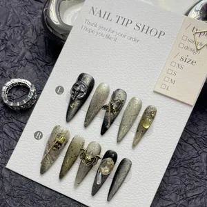Detailed macro view of dark cat-eye press-on nails with silver skull and chain charms
