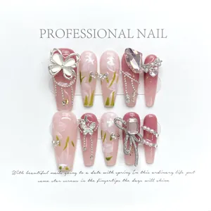 Detail of pink gradient press-on nails with 3D butterfly charms and floral patterns