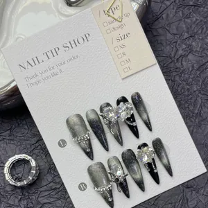 Detailed view of handmade black cat-eye press-on nails with silver butterfly and rhinestones