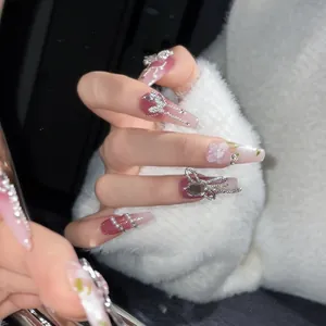 Detail of pink gradient press-on nails with silver 3D bows, pearls and floral accents