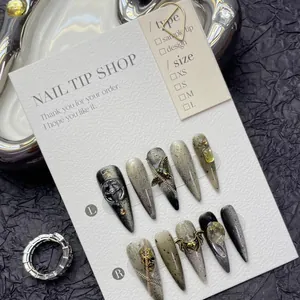Detailed macro view of Gothic black cat-eye nails with silver crosses and metallic chains