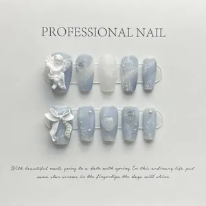 Detail of handmade press-on nails featuring marble texture and 3D angel sculpture