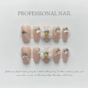 Dettaglio di unghie finte fatte a mano con strass a cuore e fiocchi 3D eleganti e chic