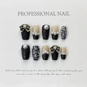 Detail of 3D embossed black chain and camellia bow on handmade press-on nail set
