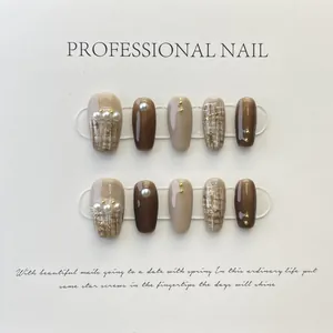 Close-up of handmade press-on nails with plaid patterns and 3D pearl embellishments