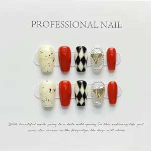Detail of handmade press-on nails featuring red, checkered patterns and heart rhinestones