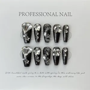 Detailed view of handmade black press-on nails with 3D embossed heart and star rhinestones