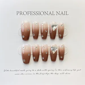 Detail of brown ombre press-on nails with heart-shaped crystal and scattered rhinestones