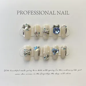 Detail of handmade cream press-on nails featuring blue rhinestones and silver butterfly