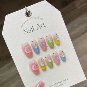 Handmade gradient macaron press-on nails with 3D star and moon charms on a display card